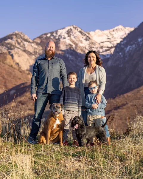 Family of four with two dogs in front of the Wasatch Mountains