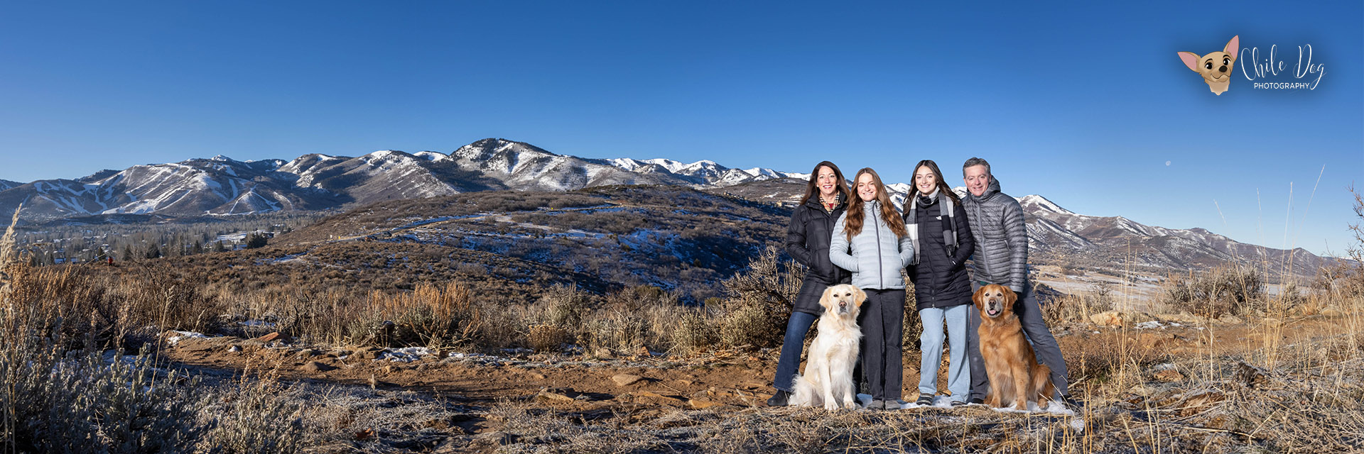 Panoramic family portrait in fron of the Park City Mountain ski slopes with a Golden Retriever and an English Cream Retriever.