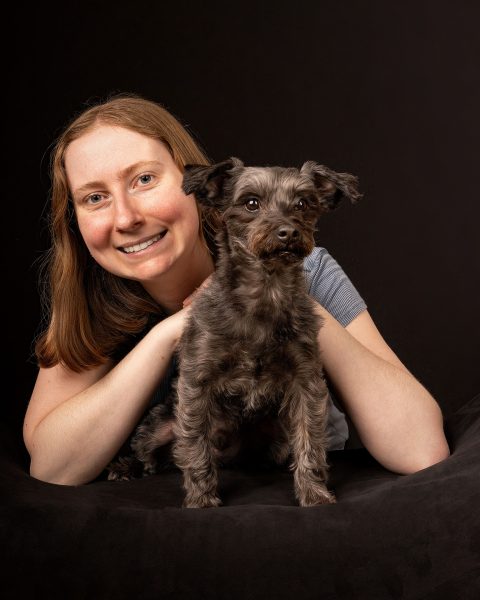 A low-key portrait of Romeo, a dark gray Yorkipoo with red in his beard and his mom, Lauren showing the human-animal bond.